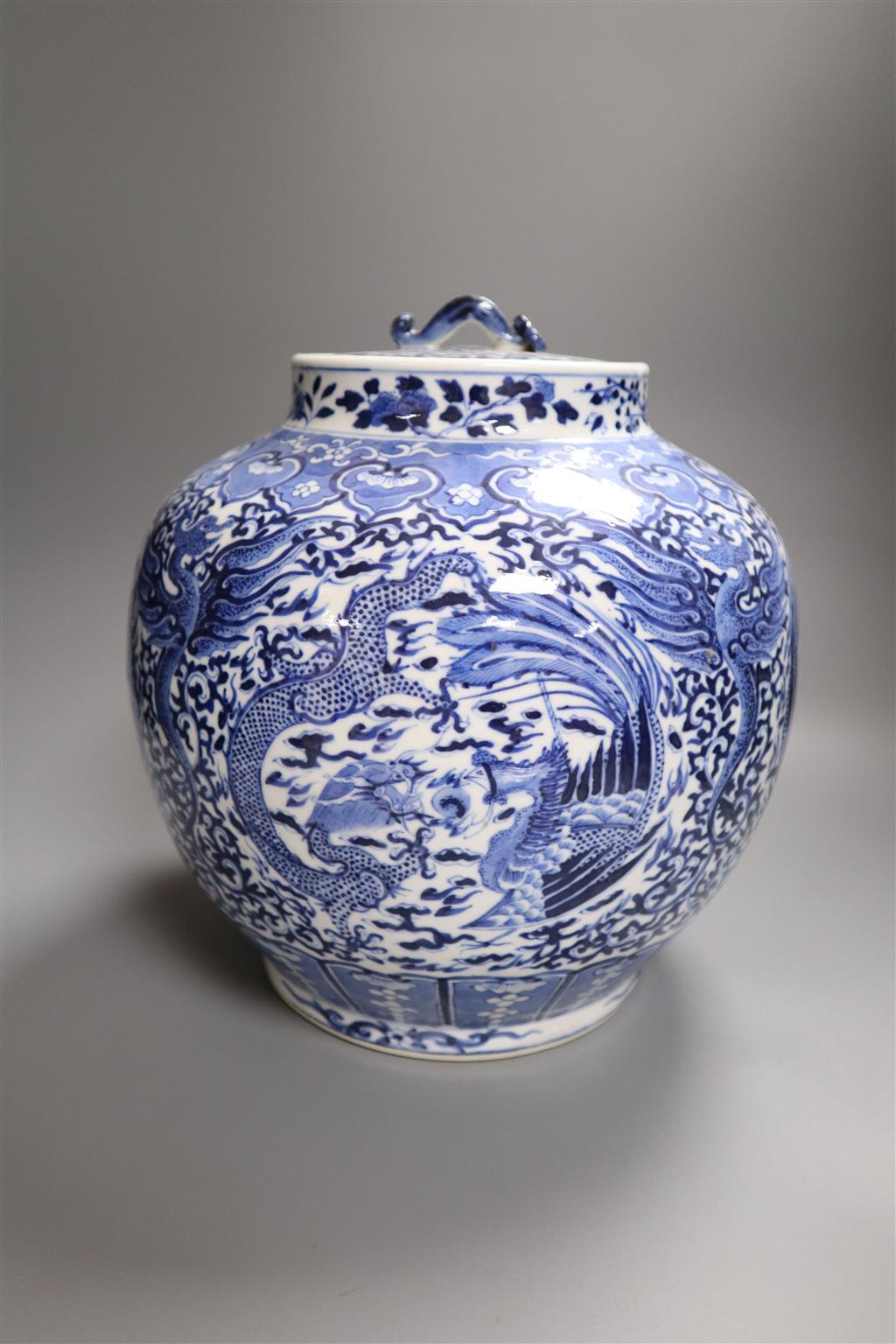 A 19th century blue and white water jar and cover, painted with dragons and birds, with inner cover and two later jars and covers